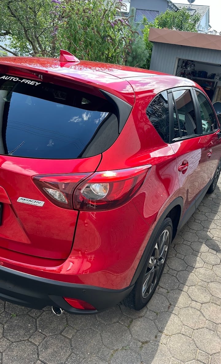 Red compact SUV on driveway rear three-quarter view