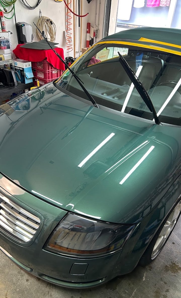 Green sedan with open hood and yellow racing stripes