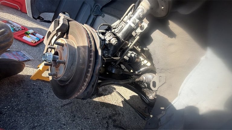 Disassembled car brake system showing rotor, caliper, and mechanical components on work surface