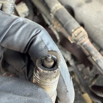 Close-up of a corroded and encrusted bolt or industrial fastener held in a gloved hand