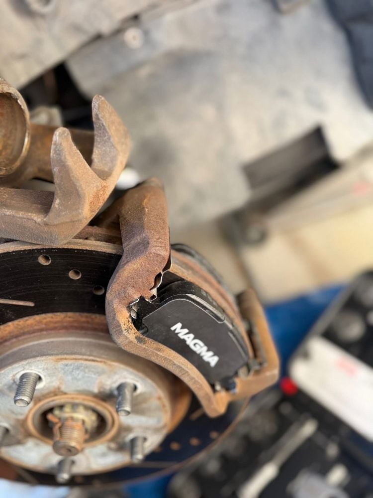 Close-up of new brake pads installed on a vehicle brake caliper and rotor