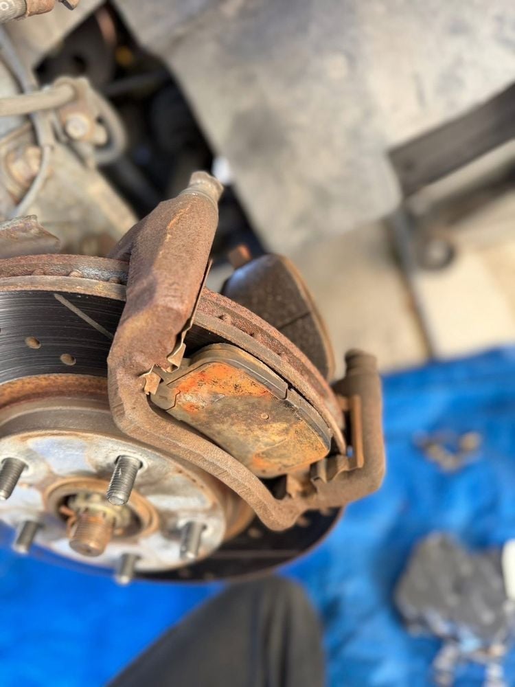 Close-up of worn brake pads on a vehicle wheel before replacement