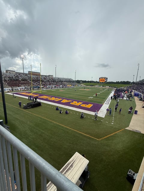 Large football stadium with purple and gold field, crowded stands, and overcast sky viewed from upper deck