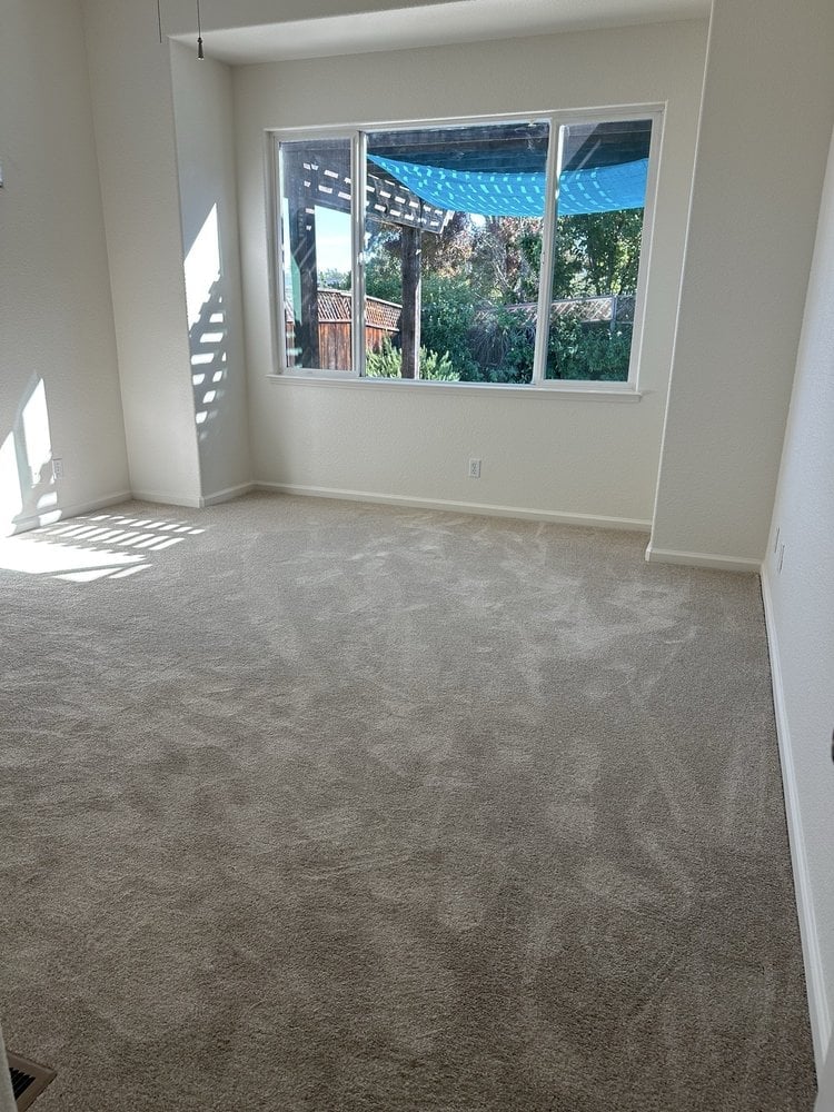 Empty room with gray carpet flooring, white walls, and large windows overlooking mountains and trees
