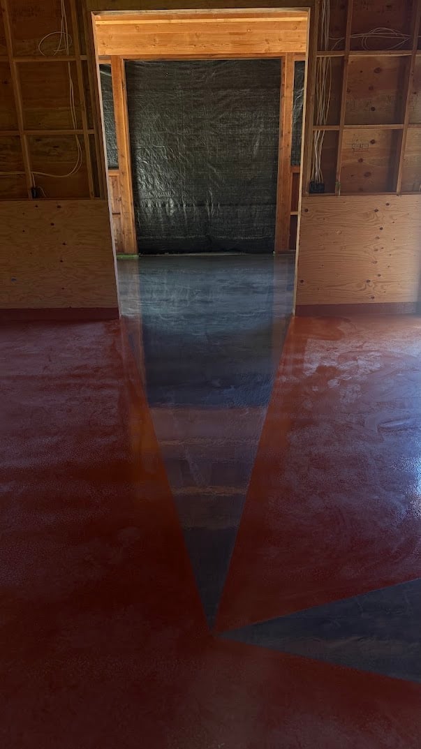 Empty wooden-framed doorway with dark mesh screen in an open room with polished concrete flooring reflecting light