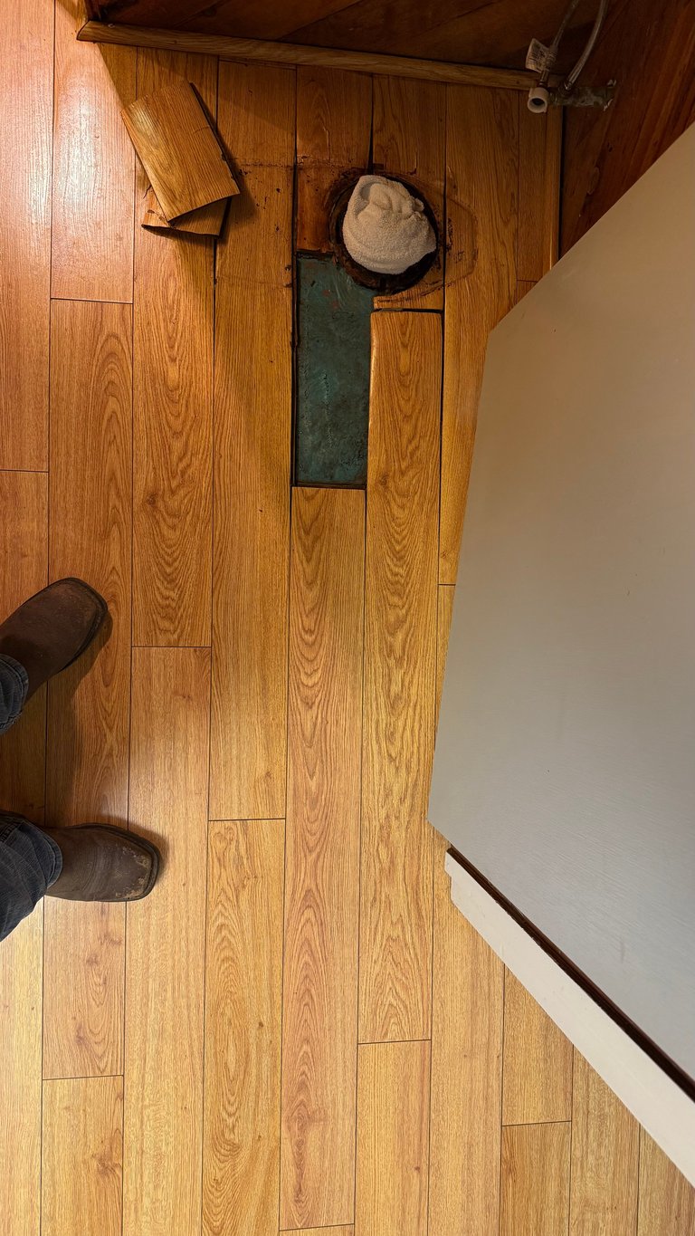 Overhead view of wooden floor with damage cutout near shelving unit and beige hat on shelf