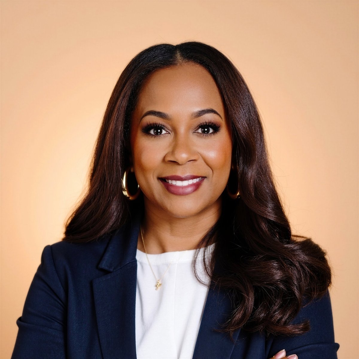 Professional headshot of Janel Woodard, founder of The Working Partnership, smiling in a navy blazer and white top against a warm beige background