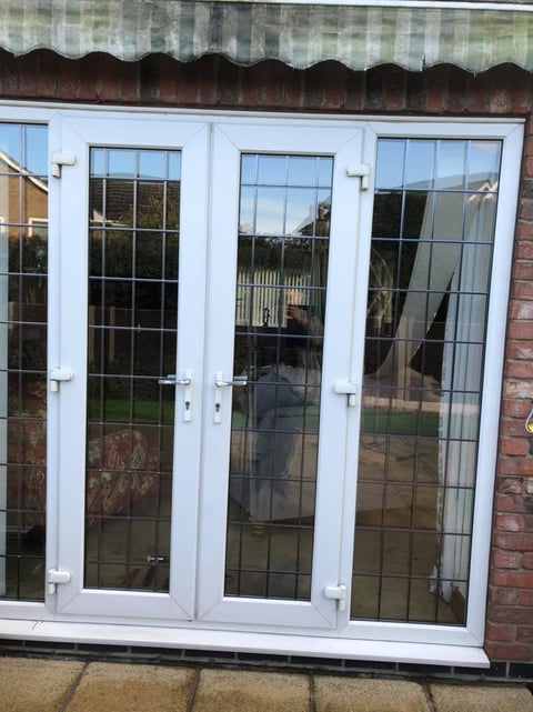 White uPVC French doors with gridded glass panes attached to a brick building with an awning above