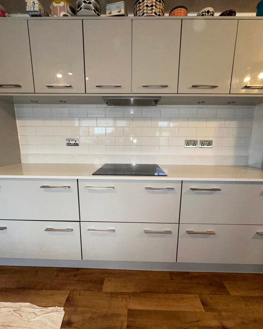 Modern kitchen with white cabinetry, white subway tile backsplash, stainless steel cooktop, and wooden flooring