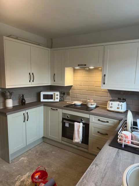 Modern kitchen with white cabinetry, dark countertops, built-in oven, and subway tile backsplash