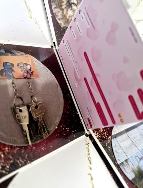 Jewelry display with metallic disc featuring dangling key charms and pink card with red lines nearby