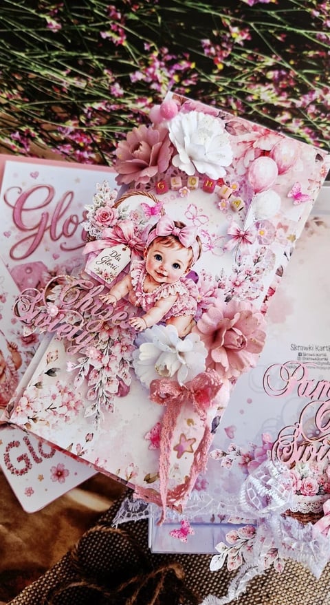 Ornate pink and white scrapbook layout with baby girl image, flowers, and decorative elements featuring lace and embellishments