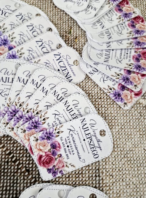 Collection of decorative nail file labels with floral designs in purple, pink, and cream colors arranged on beige fabric