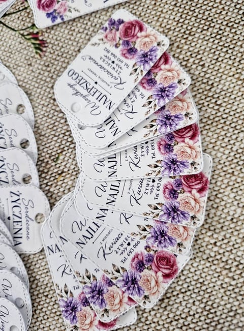 Fanned arrangement of wedding fan programs with floral design featuring purple and pink roses on white background