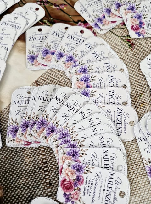 Collection of nail polish color swatches with floral designs in purple and pink tones arranged on a neutral linen surface