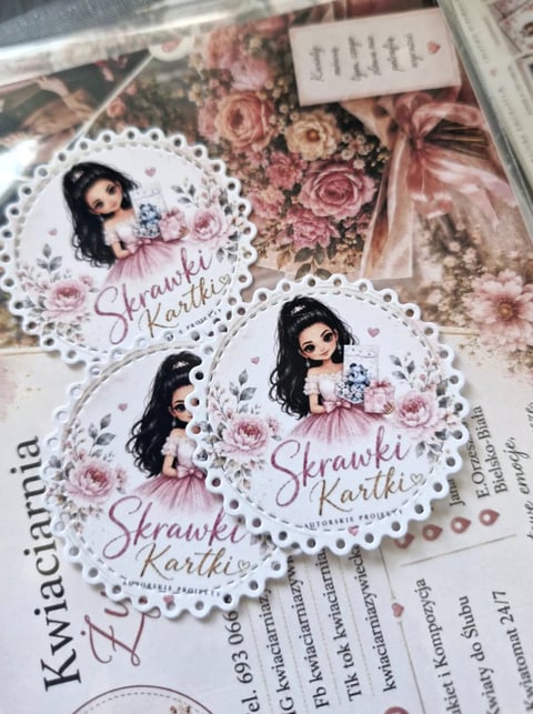 Three decorative gift tags with illustrated girls, pink flowers, and Skrawki Kartki text on white doilies with floral background