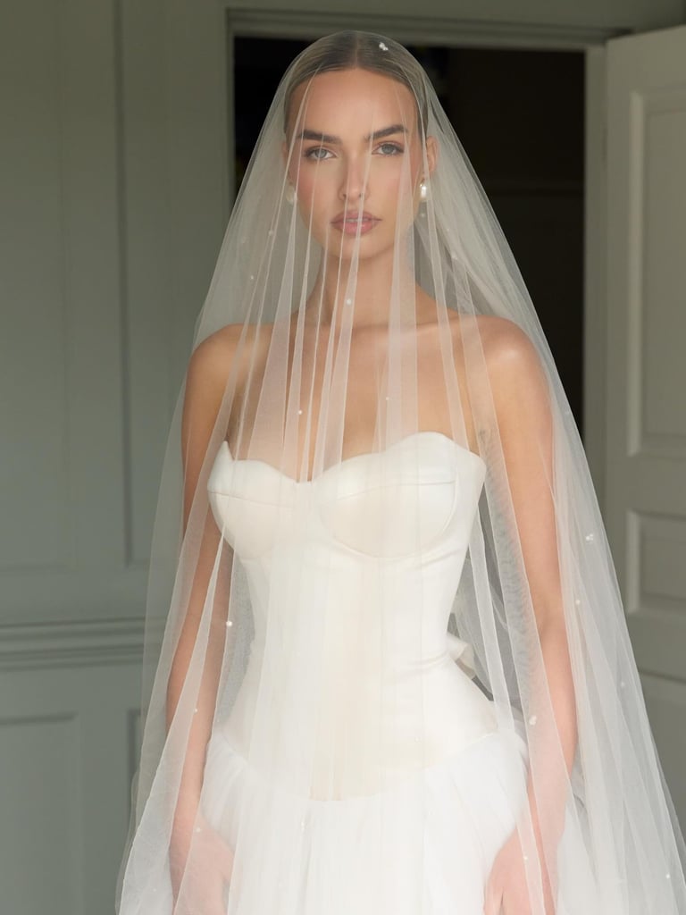 Woman in white strapless wedding dress wearing long sheer veil with pearl embellishments