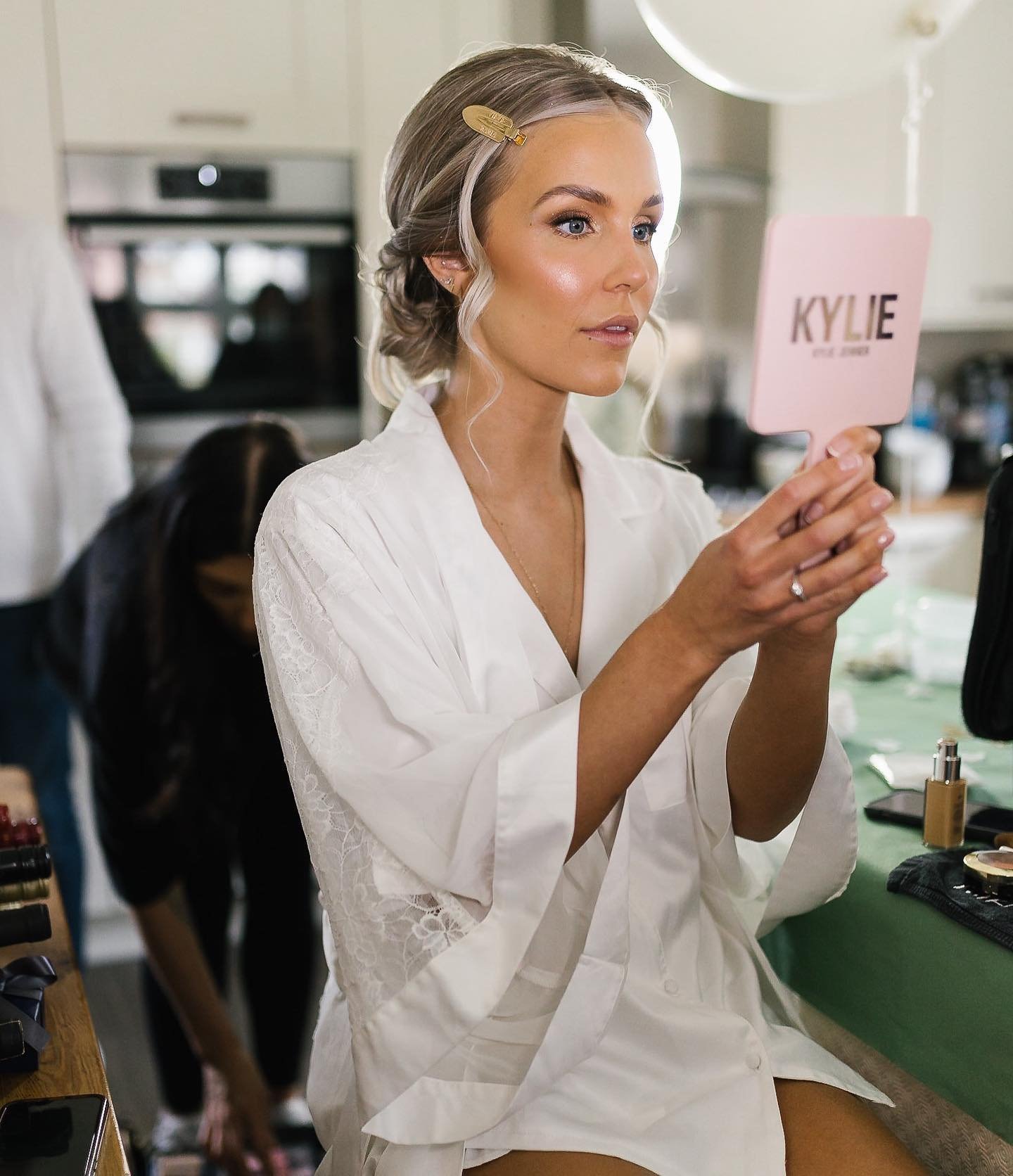 Bride in a white robe looking to the side in a bright modern setting