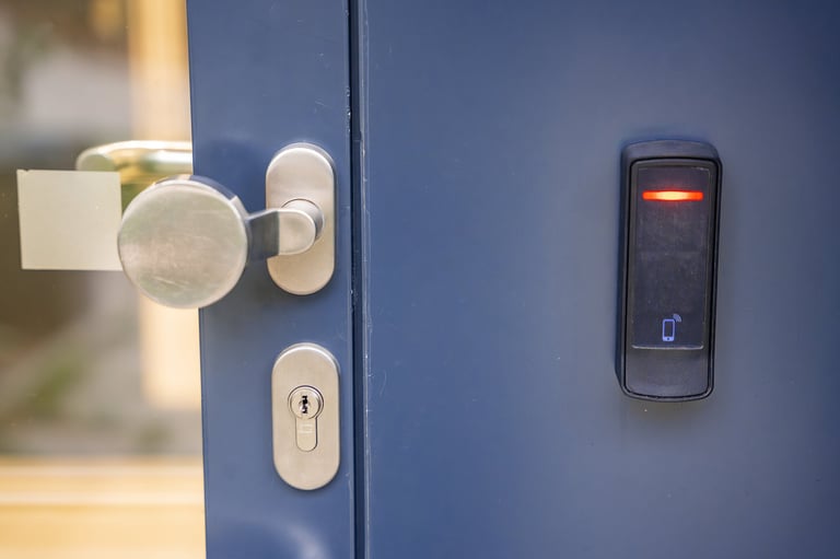 Modern door lock with silver handle and electronic card reader with red indicator light on blue door