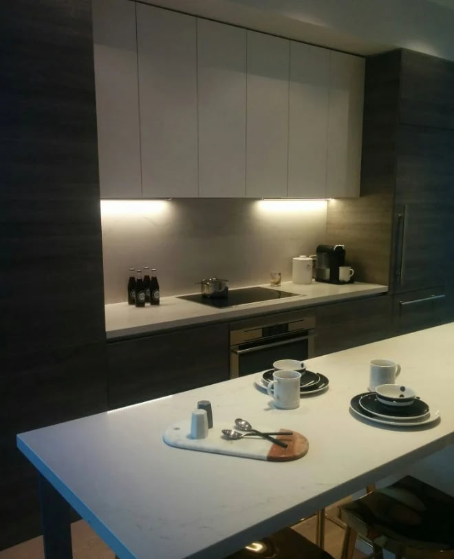 Modern kitchen with white upper cabinets, black lower cabinets, and white island counter with place settings and kitchen utensils