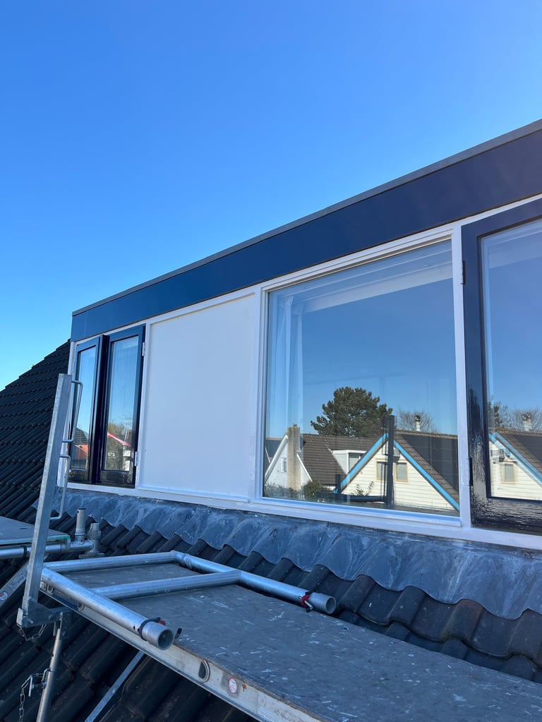 Moderne woning met blauwe kozijnen en donkere dakpannen tegen blauwe lucht