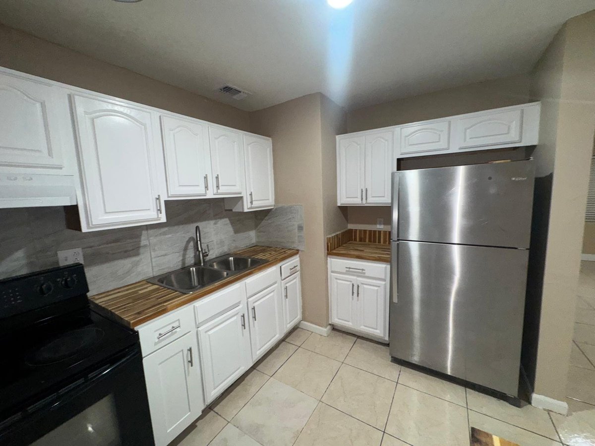 Modern kitchen with white cabinetry, stainless steel appliances, and wood countertops