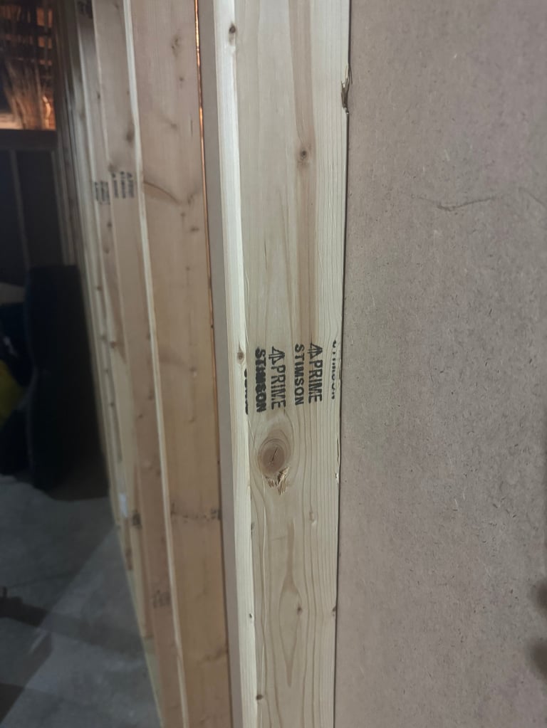 Stack of lightweight lumber boards with printed text labels leaning against a wall