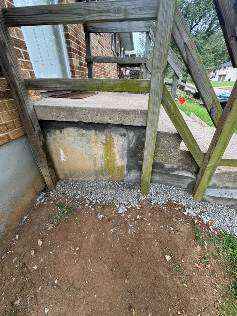 Weathered wooden gate and fence with brick wall and dirt ground in residential yard