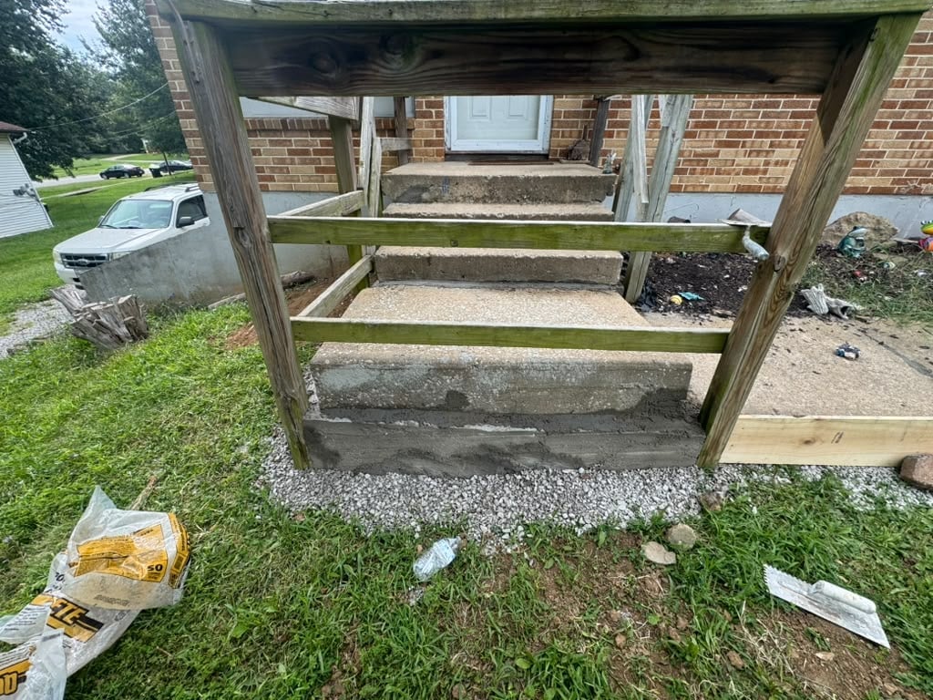 Wooden frame structure under construction in a residential yard with brick house and lawn visible in background
