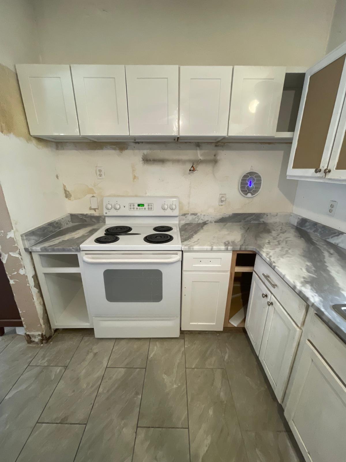 Small kitchen with white appliances, marble countertops, white cabinetry, and tile flooring