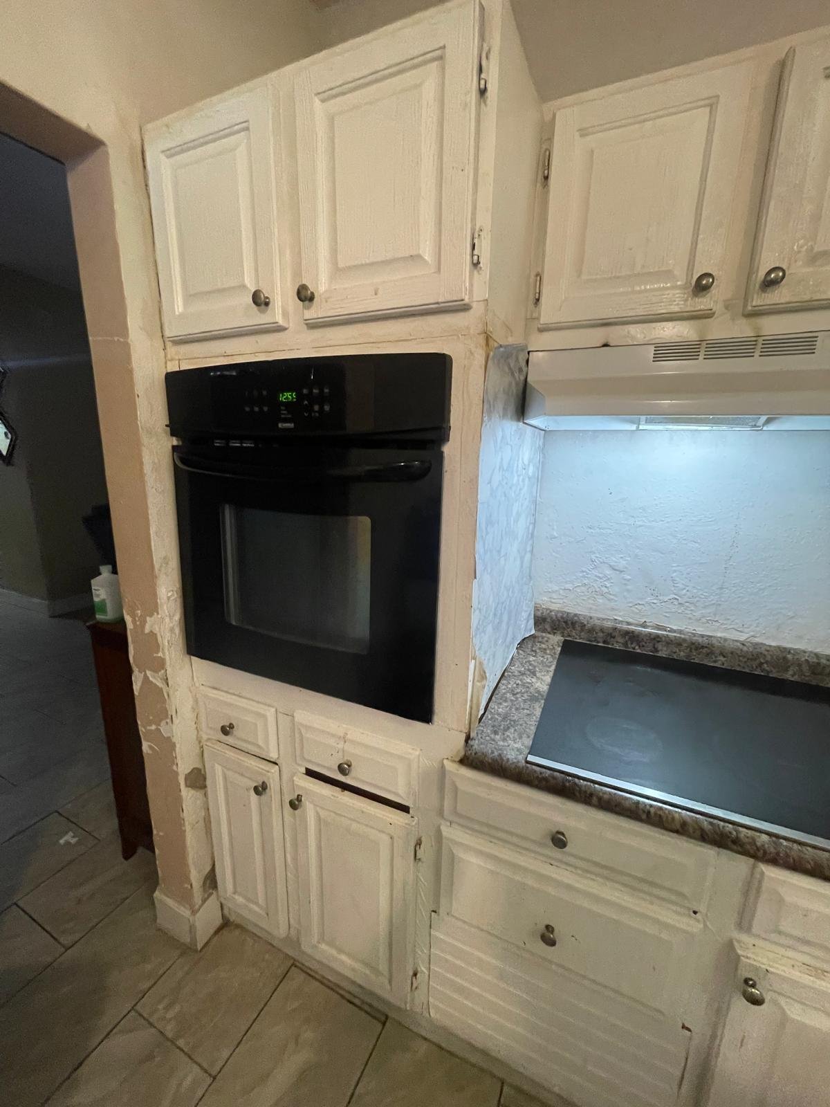 Cream-colored kitchen cabinets with a black wall oven, microwave, and stovetop appliances built into the cabinetry