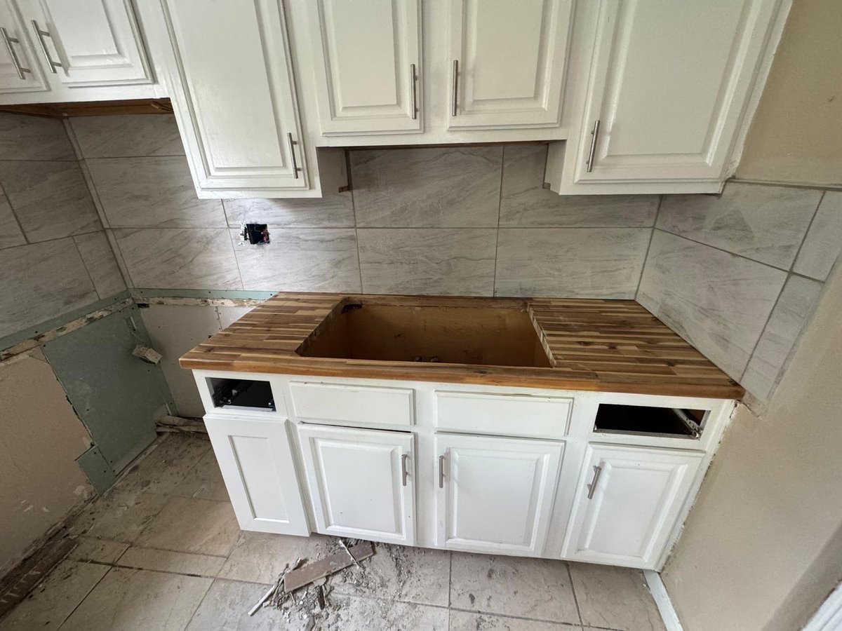 Kitchen island under renovation with white cabinets, wooden countertop removed, and exposed interior cavity during remodeling