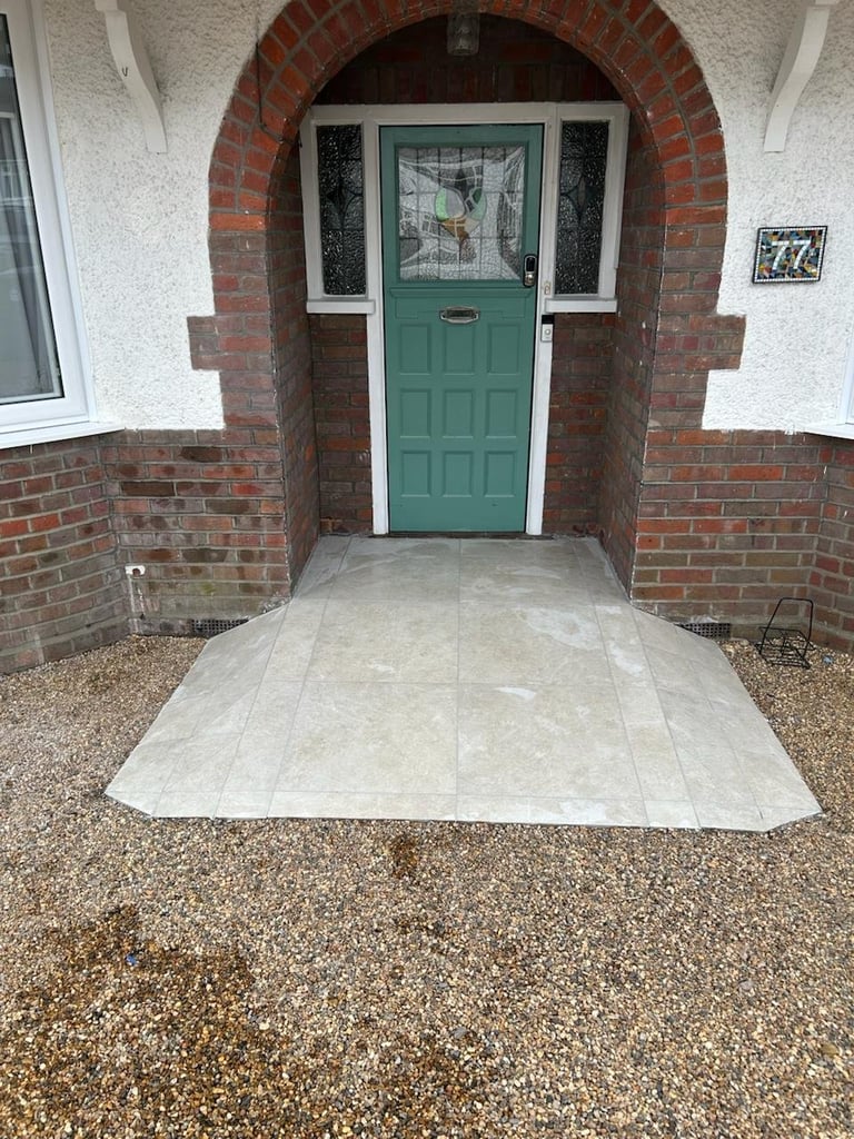 Newly tiled entrance pathway in front of a green front door with arched brick entryway
