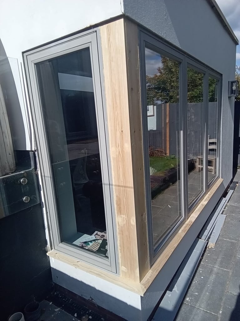 Modern garden pod with dark framed glass doors and natural wood cladding on a paved surface