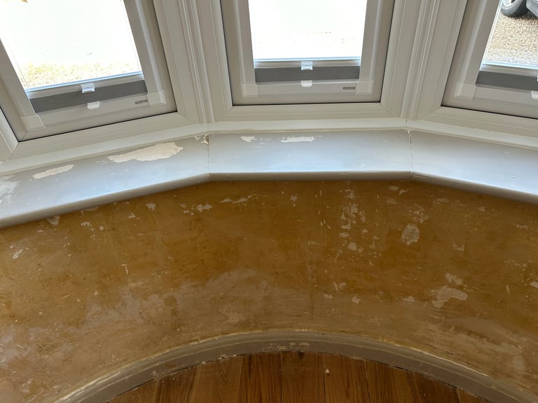 Bay window with three panes showing water damage and stains on interior walls and curved trim