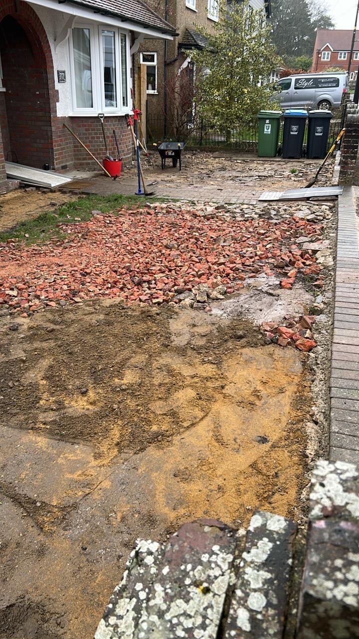 Before — muddy backyard with red clay and scattered bricks next to the brick house, prepared for the new driveway