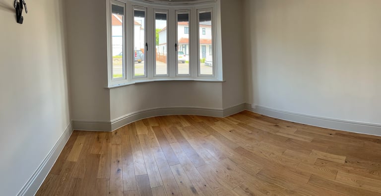 Empty room with wooden floor and curved bay window with five panes overlooking street
