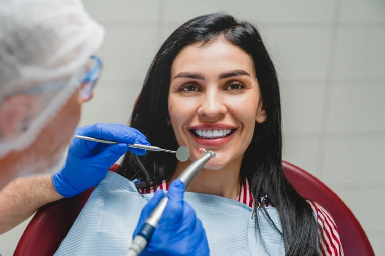 Dentist in blue gloves examining smiling patients teeth during dental appointment