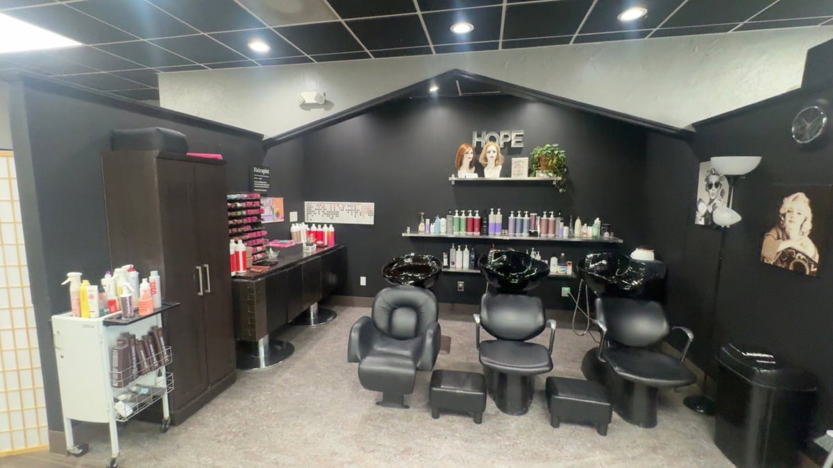 Three styling chairs in a black-walled room with the HOPE sign and product shelves