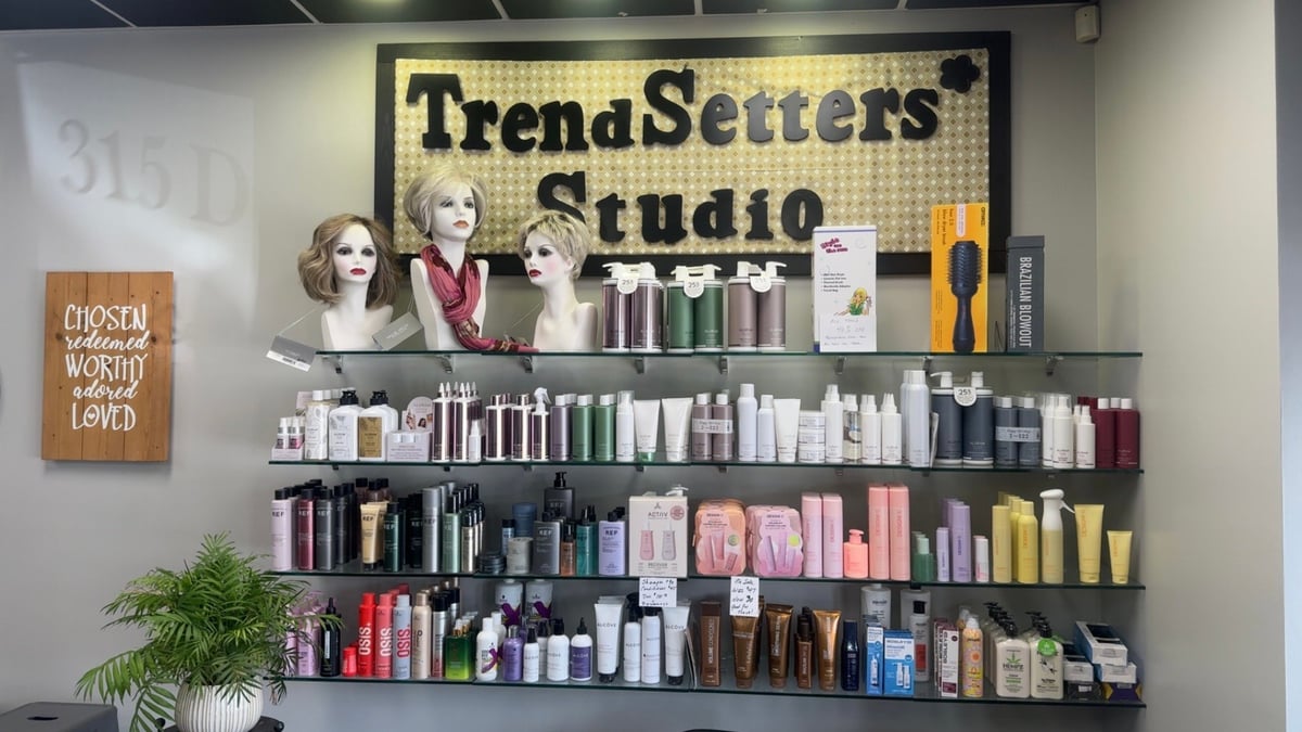 TrendSetters Studio storefront display with shelving units featuring beauty products, mannequins with styling samples, and a branded sign