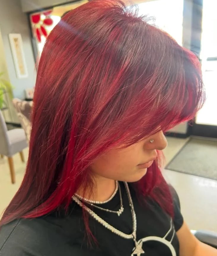 Vibrant burgundy and red shoulder-length hair styled with side bangs.