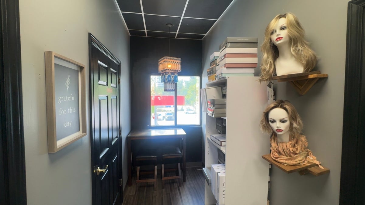 Salon shop interior with two mannequin heads on the wall and a doorway with neon sign