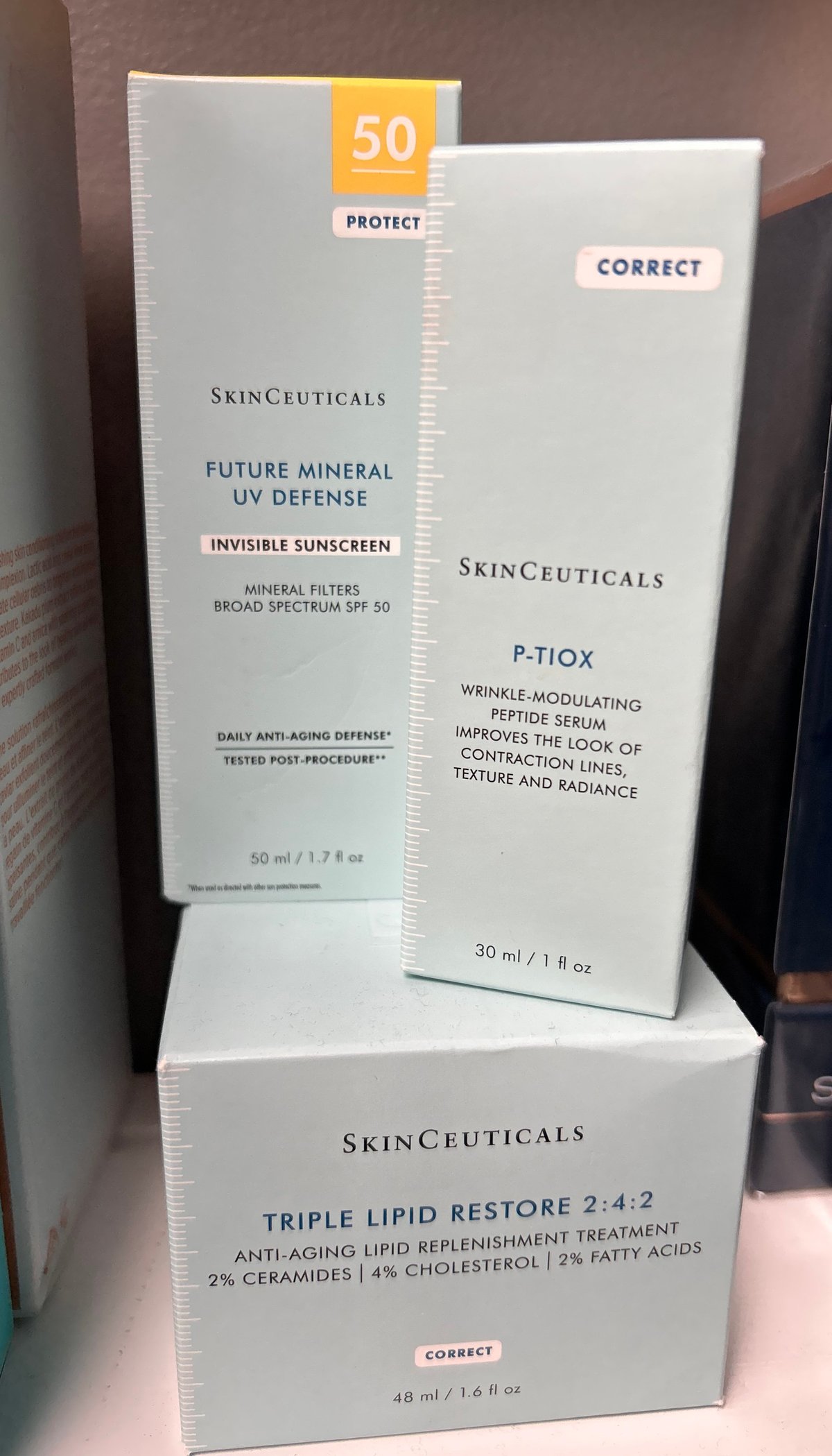 Three SkinCeuticals skincare products displayed: Future Mineral UV Defense SPF 50 sunscreen, P-Tiox wrinkle-modulating peptide serum, and Triple Lipid Restore 2:4:2 anti-aging treatment.