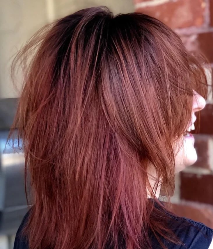 Side view of shoulder-length burgundy red hair with layers and darker roots.