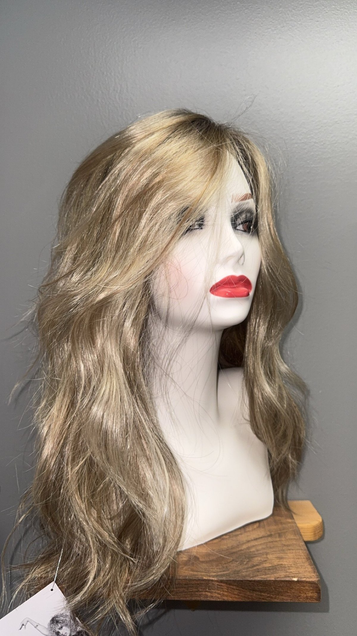 Mannequin head displaying a long wavy brunette wig with bangs.