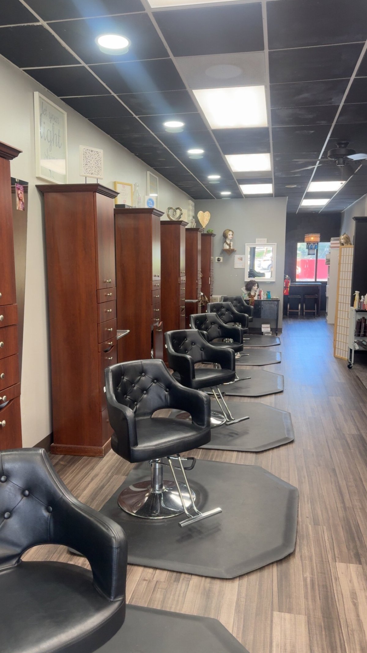 Interior of Trendsetters of Hendersonville with black styling chairs, wooden storage cabinets, and LED ceiling panels