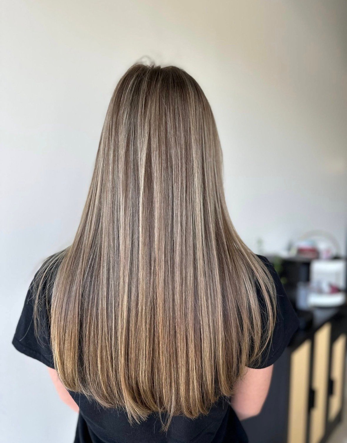 Back view of long, straight, highlighted brown and blonde hair, mid-length.