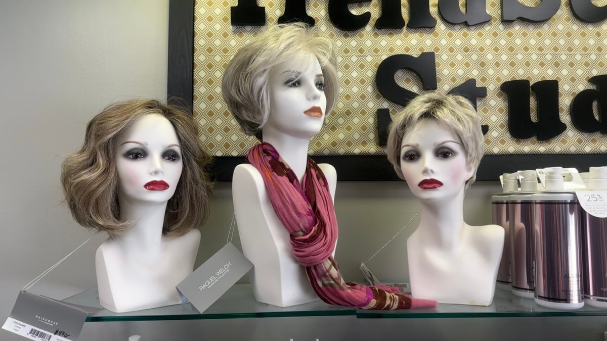 Three mannequin heads displaying blonde wigs of varying lengths, one wearing a burgundy scarf.