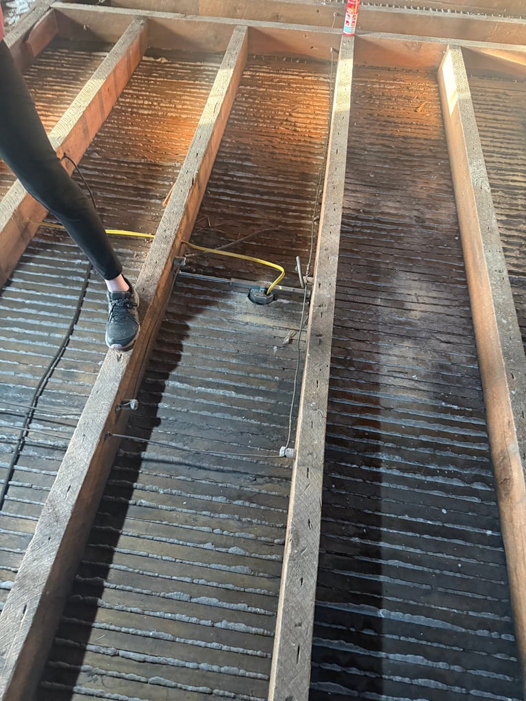 Person power washing wooden deck sections with multiple parallel planks, using a pressure washer spray