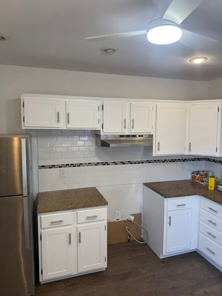 Modern kitchen with white cabinetry, stainless steel appliances, granite countertops, and subway tile backsplash